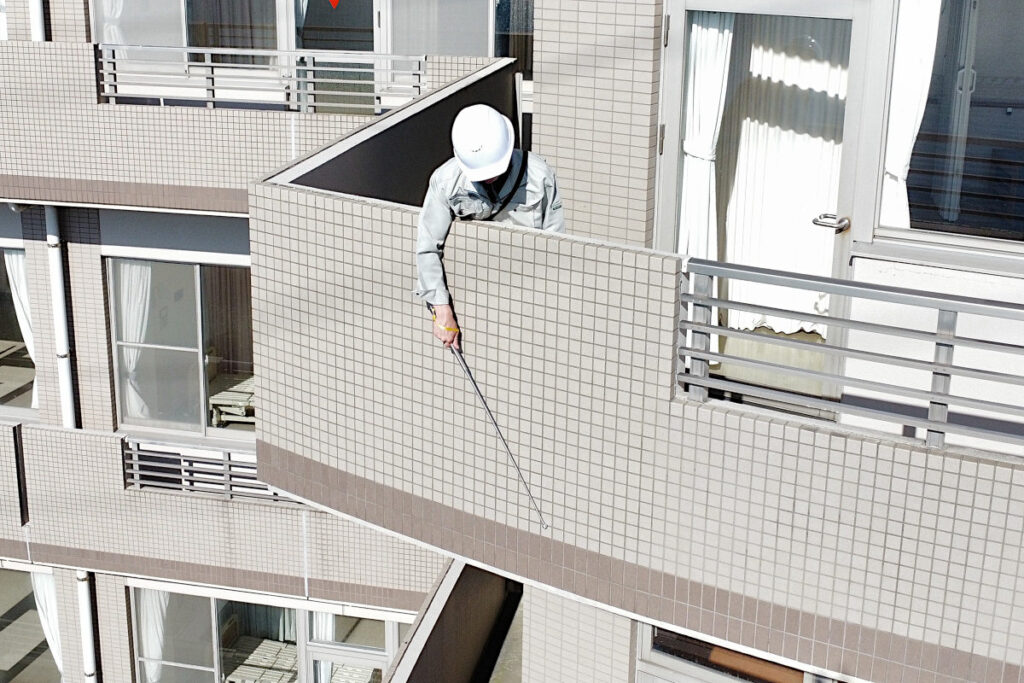 廊下から打診棒で調査する調査員